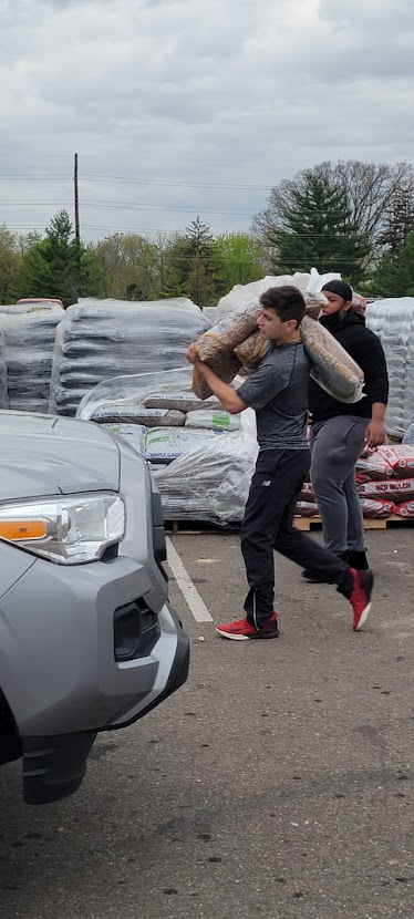 Football player carrying bag of mulch.